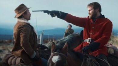 a man points a gun at another man on horseback in the settlers